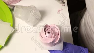 女人形成棉花糖玫瑰。 使用特殊的支架和糕点袋。 从上面看